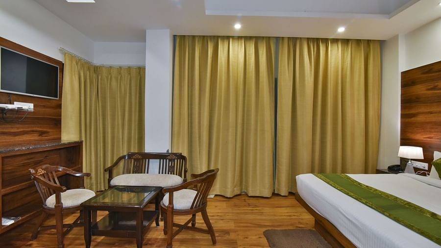 A large bed placed in front of two sofas at the Luxury Room Without Balcony at DLS Highland Resort and Spa, Mussoorie.